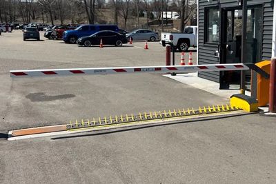 A boom barrier in a parking lot prevents cars from passing.
