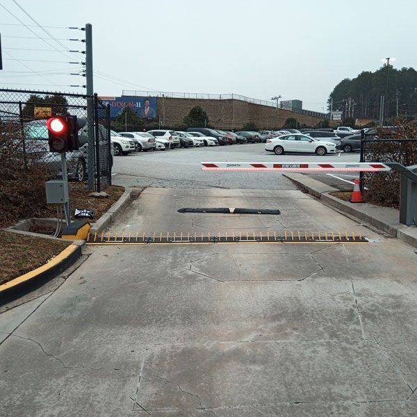 A crossing arm and a Low Profile Electric Road barrier block the exit to a parking lot, preventing car theft.