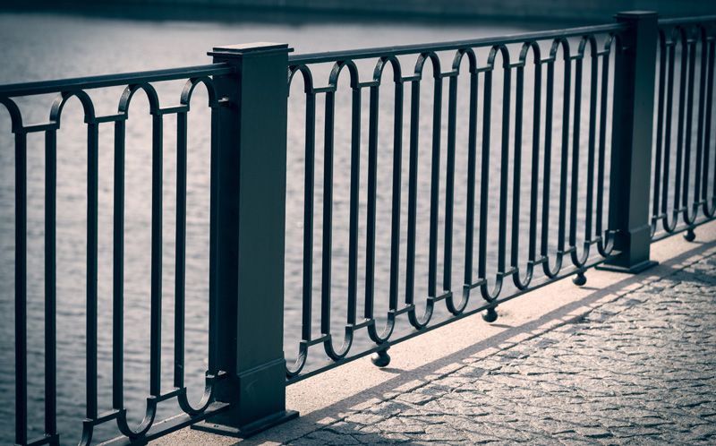 A railing in front of a body of water prevents pedestrians from falling into the water.